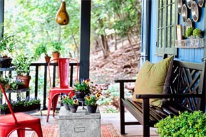 a porch with pie-tins on the wall, a bench, red metal chairs and a gourd birdhouse