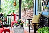 a porch with pie-tins on the wall, a bench, red metal chairs and a gourd birdhouse