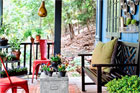 a porch with pie-tins on the wall, a bench, red metal chairs and a gourd birdhouse