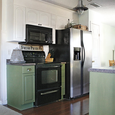 farmhouse-style kitchen after remodel with green cabinets, black appliances