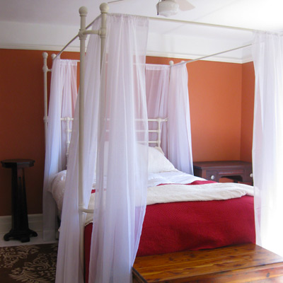 farmhouse bedroom with orange walls and canopy bed