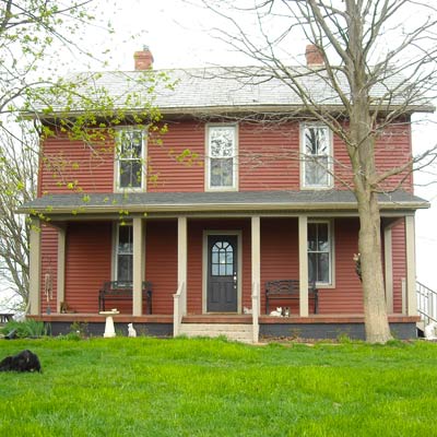 farmhouse with red siding and pavers front porch 