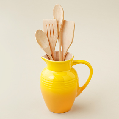 stoneware pitcher with yellow enamel finish and wooden utensils