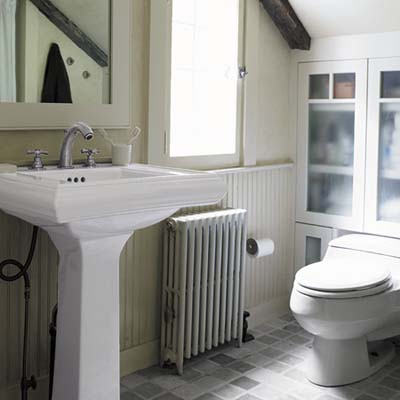 master bathroom has a pedestal sink, custom cabinets, marble floor tiles and radiant heating