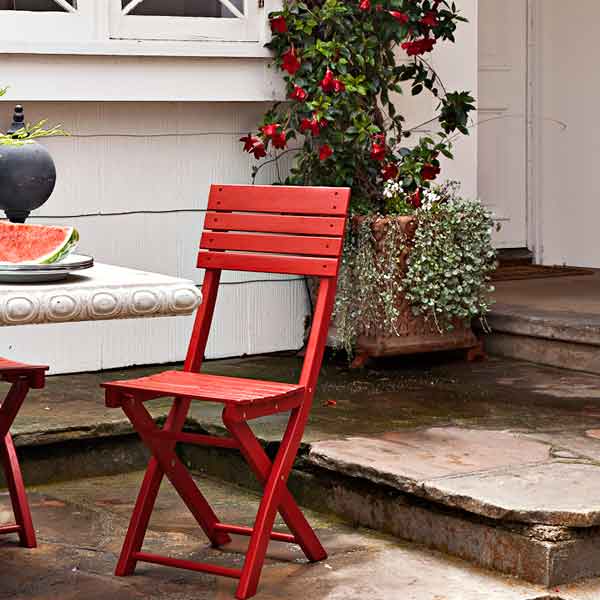 upgrade outdoor room, patio with concrete table and red painted chairs, vine creeping along adjacent window