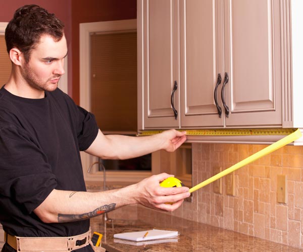 man measuring kitchen cabinet