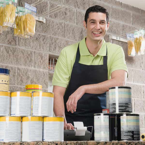 man behind counter at hardware store with paint supplies