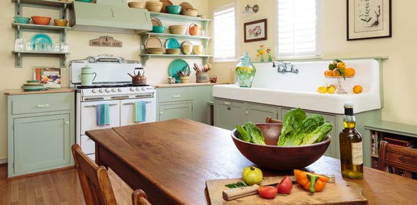 retro style kitchen with soft green cabinets and salvage apron sink