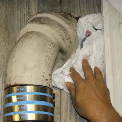 plastic bag being stuffed between pipes and drywall