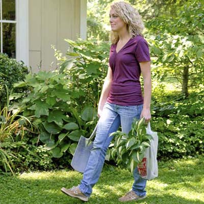 woman holding a shovel, carrying plant in a plastic bag