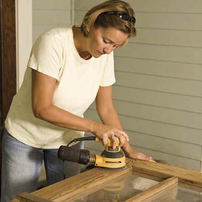 renovation pro Kara O'Brien finishes the last bit of sanding on an old door