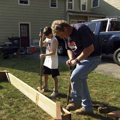 Roger Cook and young boy use edgers to mark out the perimeter of the raised bed