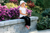 Little girl with flowers on sitting wall