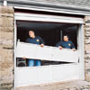 two workers dismantling a common overhead garage door