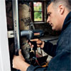 worker screwing brackets to the jamb to hold the garage door track in place