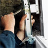 hands holding the wrench tightening the bolts of the garage door's upper tracks