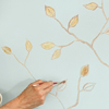 gold paint applied to leaves sketched on a wall