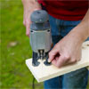 hands using a jigsaw to cut a wood board to shape for the box, top or legs of the pet ramp