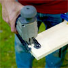 hands using a jigsaw to cut a wood board to cut the curve into the legs of the pet ramp