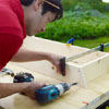 man using a drill driver to screw together the sides of the pet ramp box