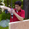 man using a drill driver to drill holes for the leg bolts