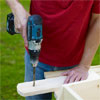 man using a drill driver to drill bolt holes in the legs
