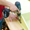 hands using a drill driver to attach a block to the underside of the lid