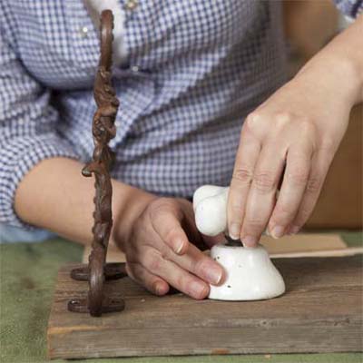hands attaching a tap to the base mounted on a board to make a vintage porcelain tap towel rack