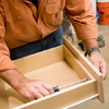 Tom Silva attaching knobs to the drawer fronts of the joined cabinets