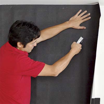 man attaching builder's felt to the front and sides of a fireplace