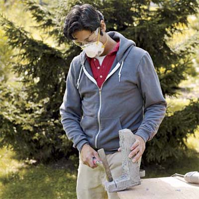 man using a hammer to remove excess mortar from corner pieces used to create a stone veneer surround