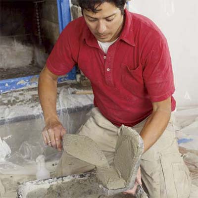 man coating the first corner pieces with mortar to create a stone veneer fireplace surround