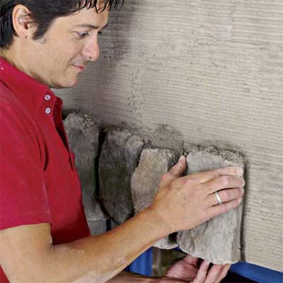man installing the header stones to create a stone veneer fireplace surround