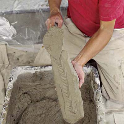 hands coating the top-left fieldstone to create a stone veneer fireplace surround