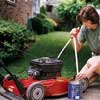 Woman emptying her lawn movwer's gas tank into an old coffee can