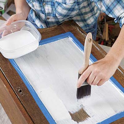 hand brushing latex primer on a cabinet door