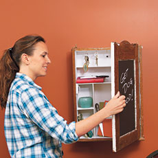 woman putting an envelope in the pocket of a message center made from a vintage medicine cabinet