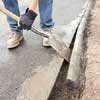 man prying a spade between asphalt that's been cut and the excess asphalt