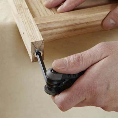 hands using an allen wrench to install the insert nuts into the legs while building a dog gate