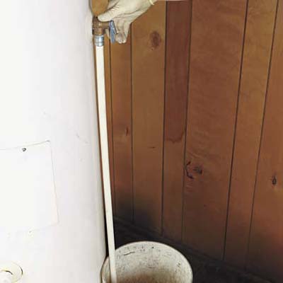 latex-gloved hand testing a TPR valve on a water heater