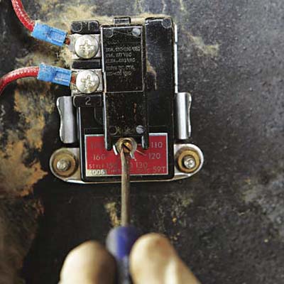 close up of a flat head screwdriver that is making adjustments to a temperature dial