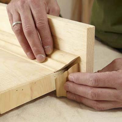 hands installing crown molding to shelf