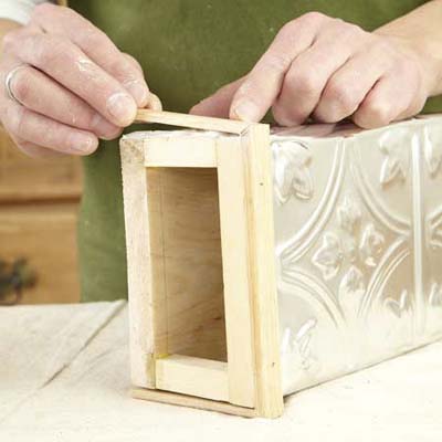 hands working with a wooden and tin box