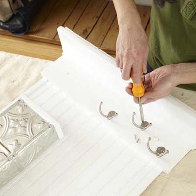 man installing hooks to wall organizer