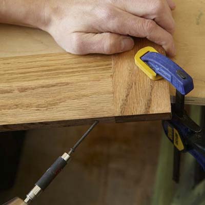Mark Powers uses a drill/driver to put a pilot hole into the door frame of a dog crate