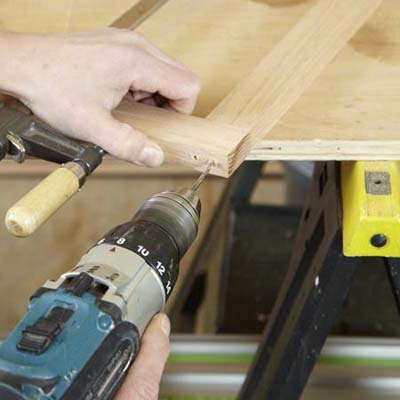 Mark Powers drills pilot holes into the face frame of a dog crate