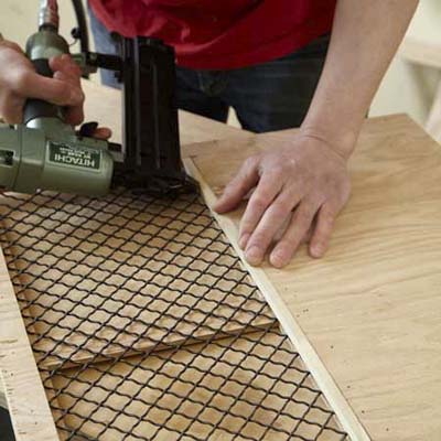 Mark Powers attaches the grille to the side windows for a side panel of a dog crate