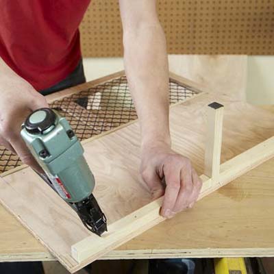 Mark Powers attaches the floor support to a side panel of a dog crate