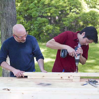 two men drilling holes in rungs for ladder golf game set