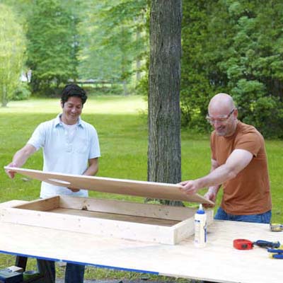 two men positioning frames for cornhole game board